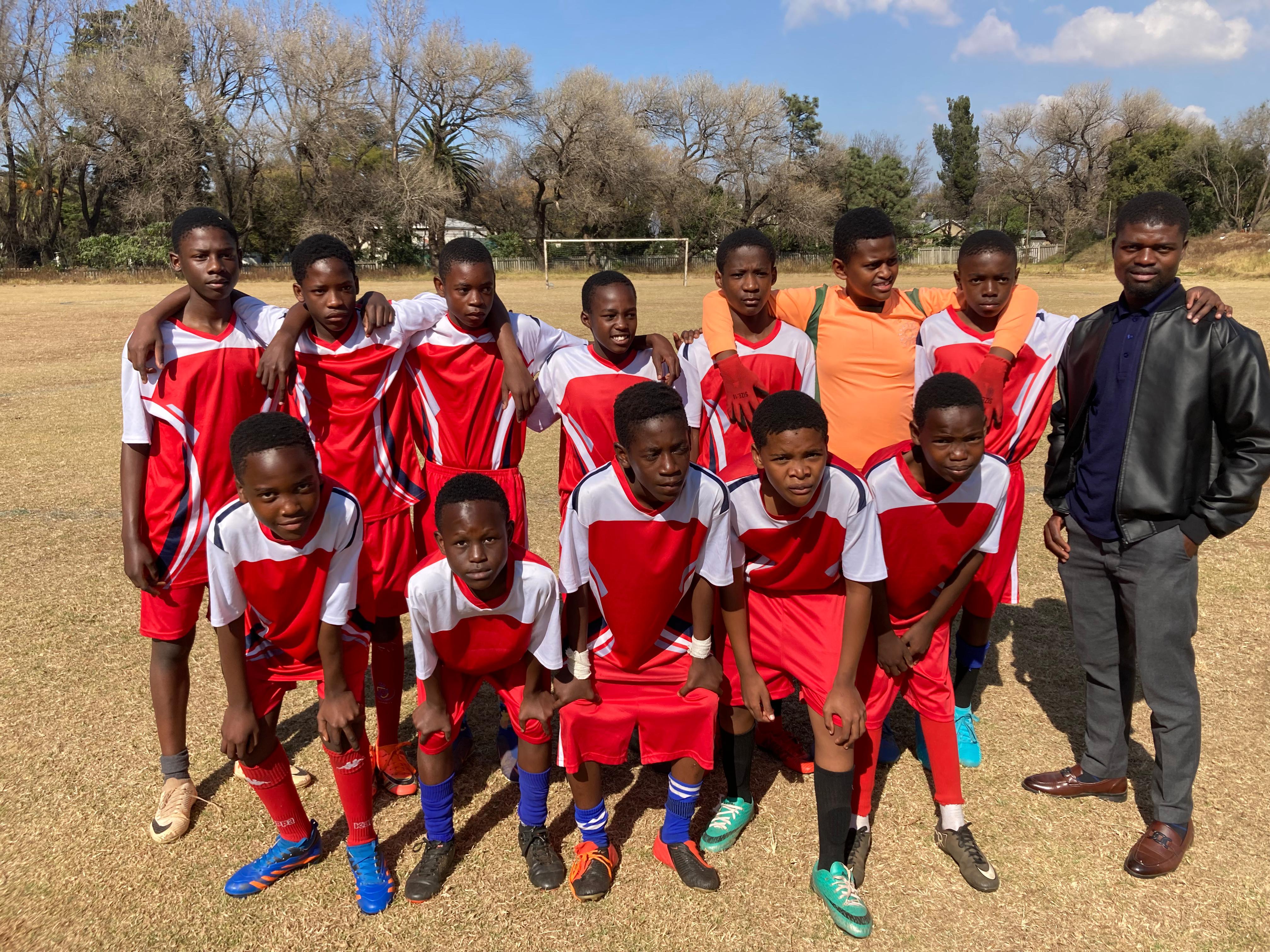 En Fuego FC youth players standing together
                            with their coach on the football field